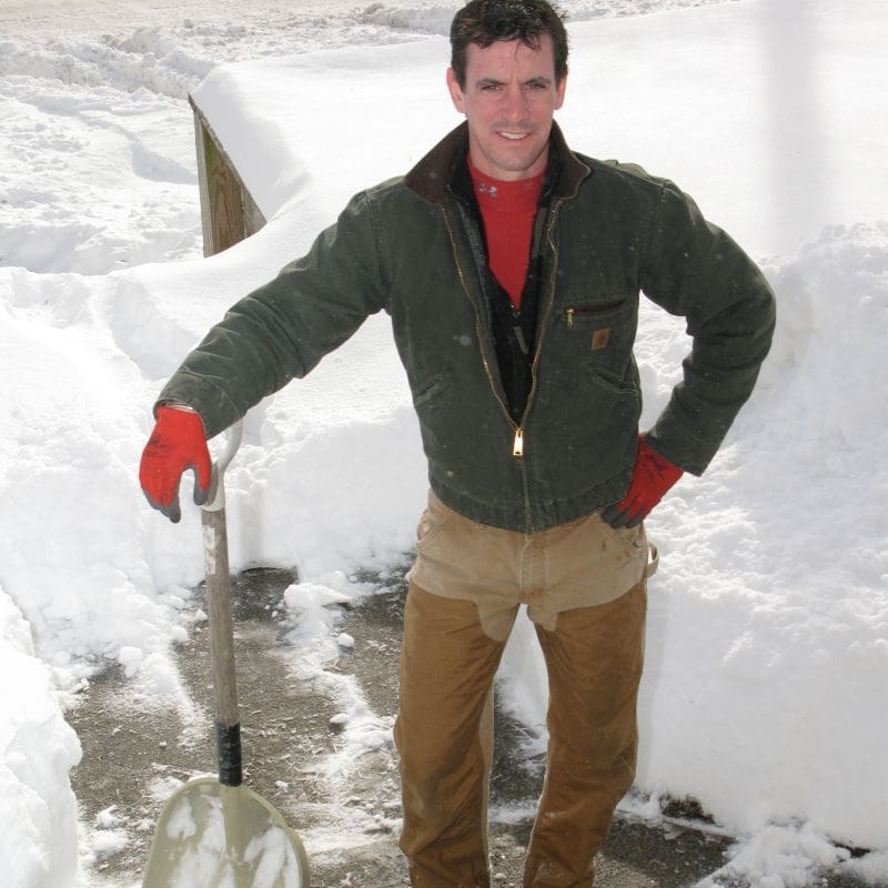 Carpenter Mark with a grain scoop shovel in the snow.